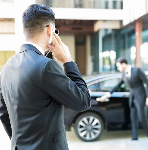 Men in suits beside black car.